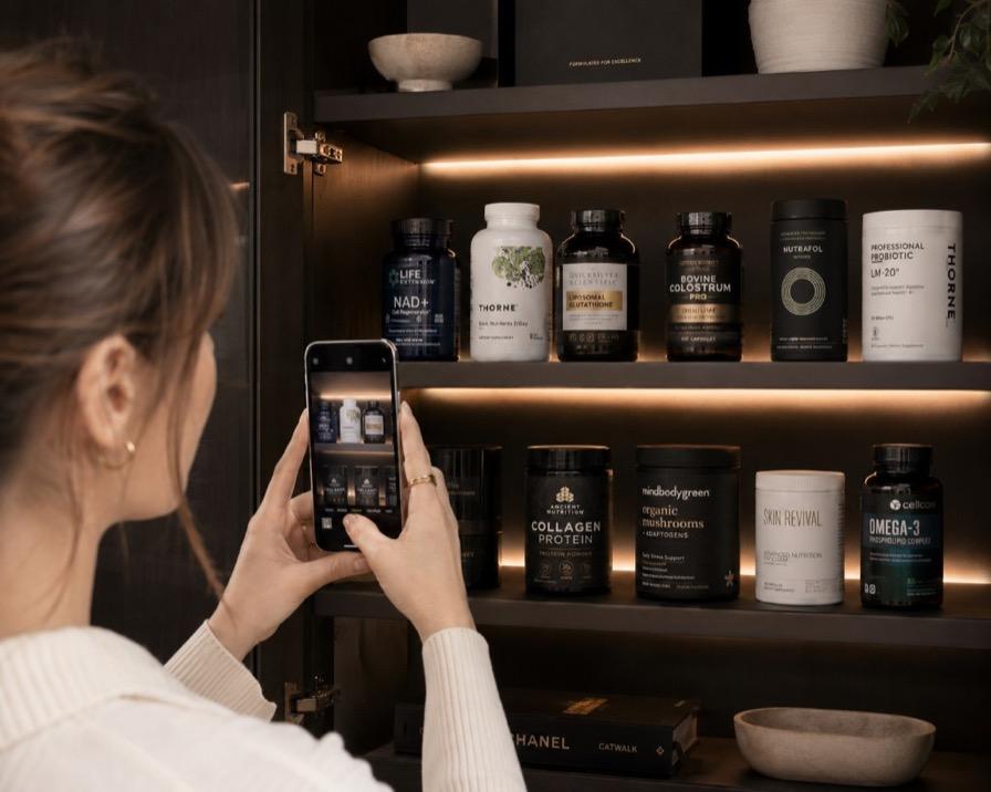 Hands holding a phone over supplement bottles on a shelf